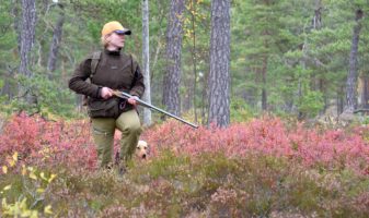 Jägaren i smygjakten med hunden.