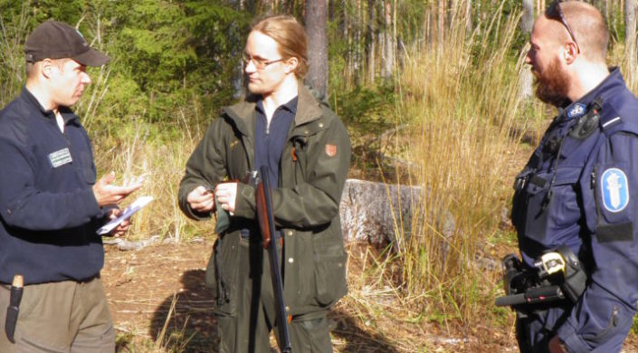Poliisi ja metsästyksenvalvoja tarkastavat metsästäjän lupia maastossa.