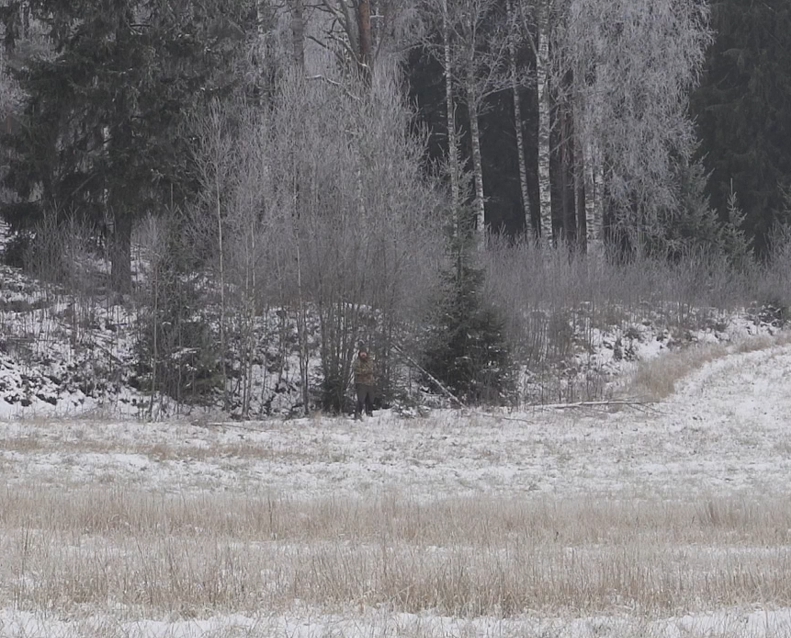 Huomioväritön metsästäjä pellon reunassa.