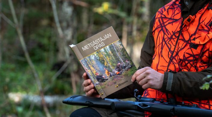 En jägare läser handboken i terrängen.