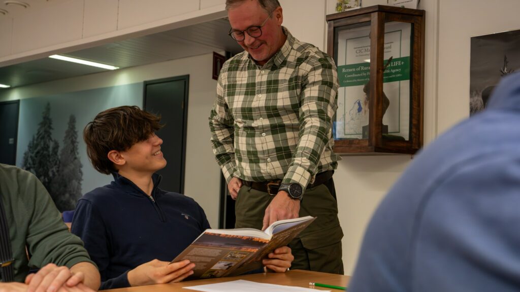 Kurssilainen lukee Metsästäjän opasta yhdessä kouluttajan kanssa.