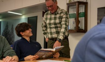 Kursdeltagaren läser Handbok för jägare tillsammans med utbildaren.